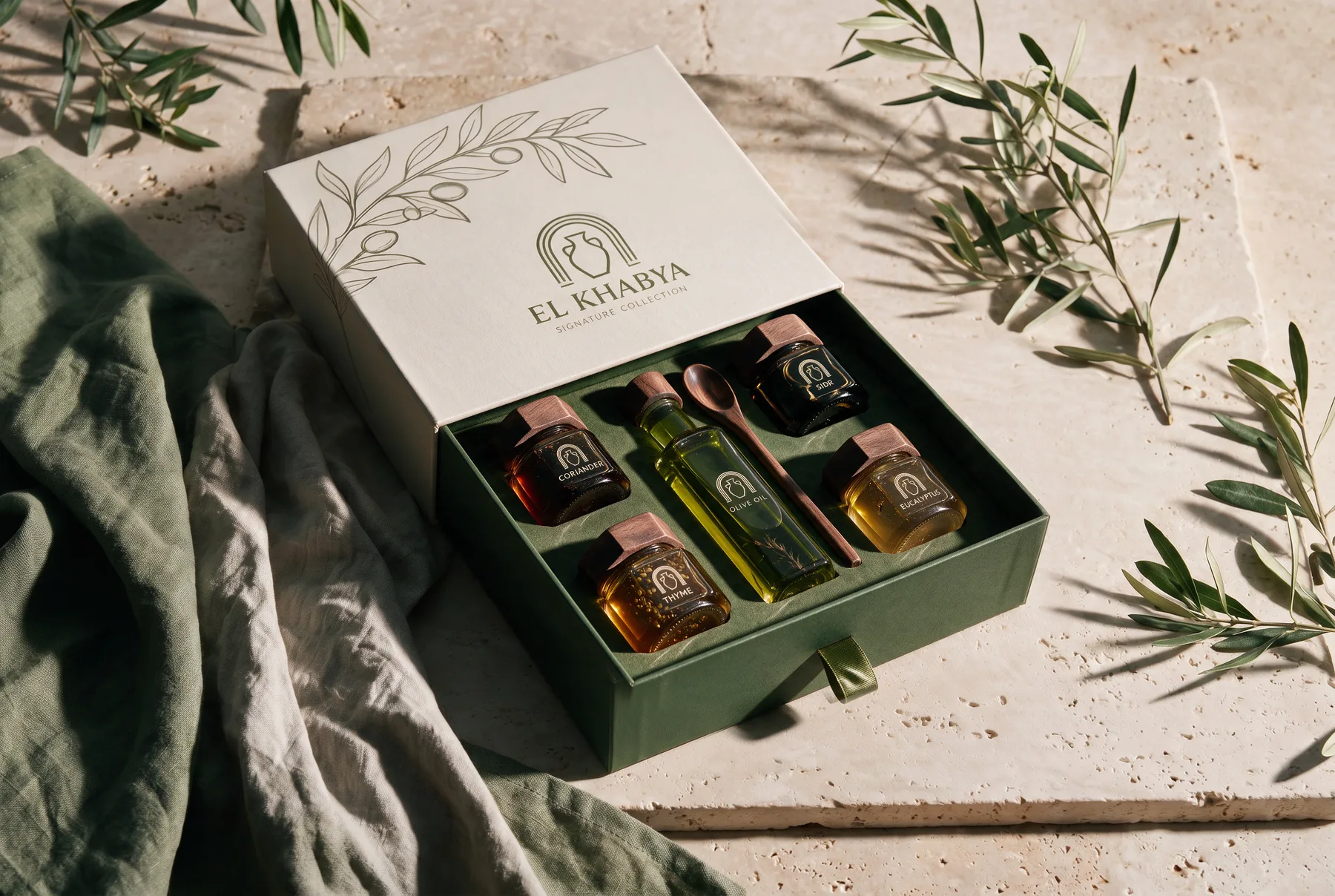 Signature Collection — geöffnete El-Khabya-Box mit veredelten Honigen und Würzöl auf Travertin